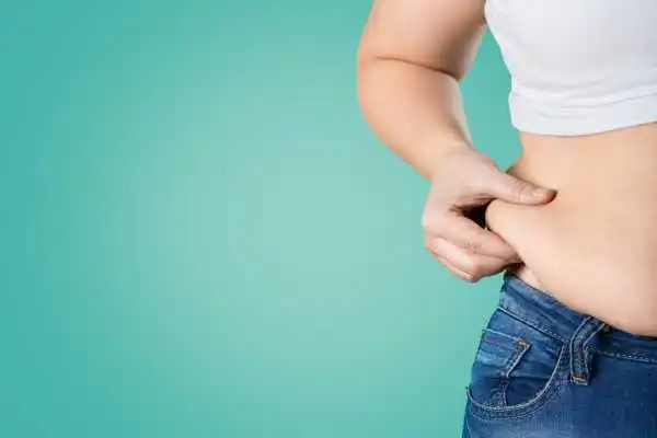 Image of woman pinching her love handles to show weight gain Lyme Regis